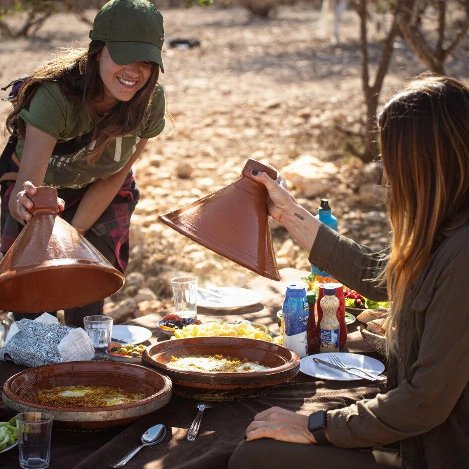 Dos viajeras compartiendo un tajine al aire libre en el Atlas