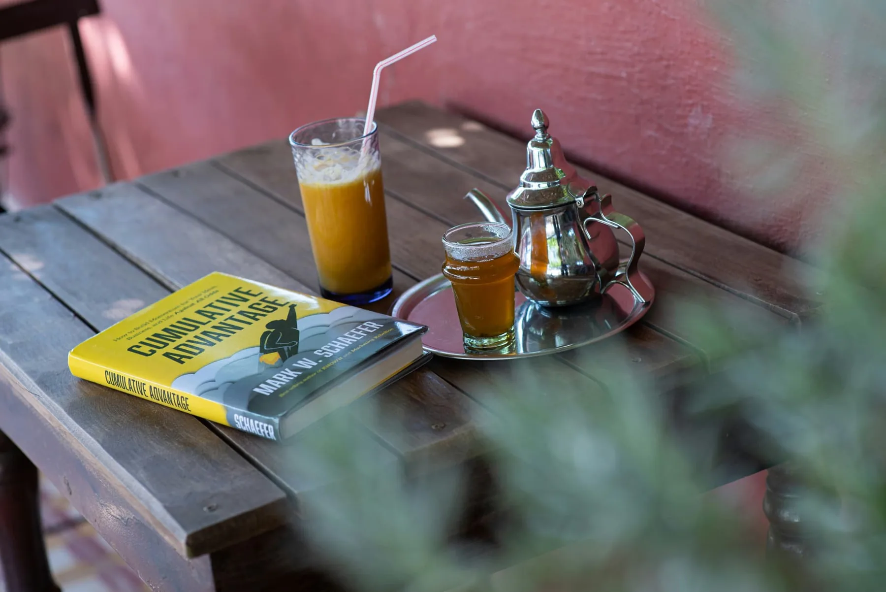 Vaso de zumo de naranja, tetera y libro sobre una mesa de madera
