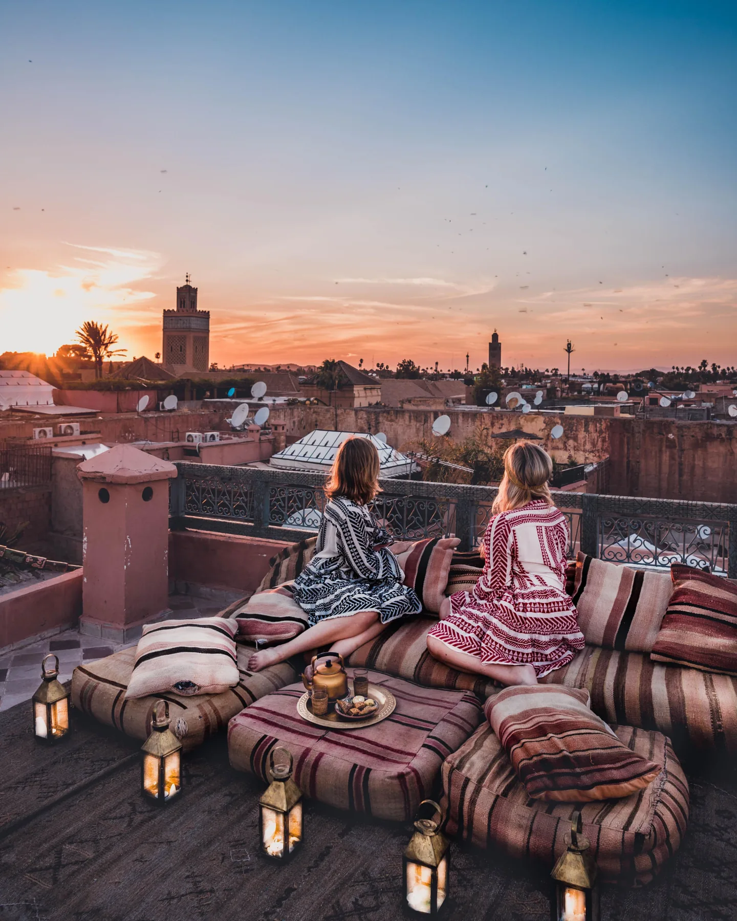 Dos amigas contemplando la puesta de sol sobre Marrakech desde la terraza