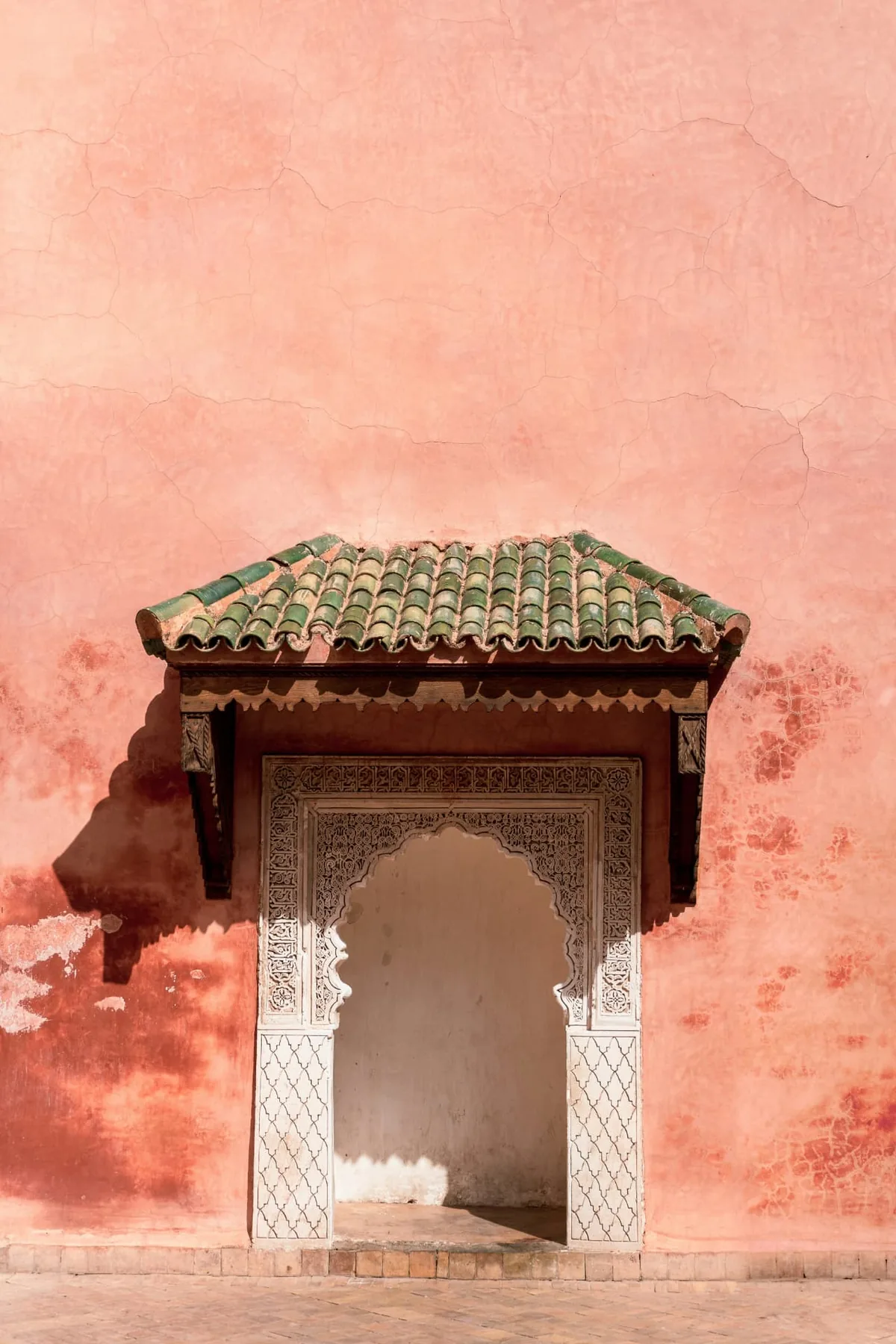 Puerta tallada tradicional en un muro rosa de la medina