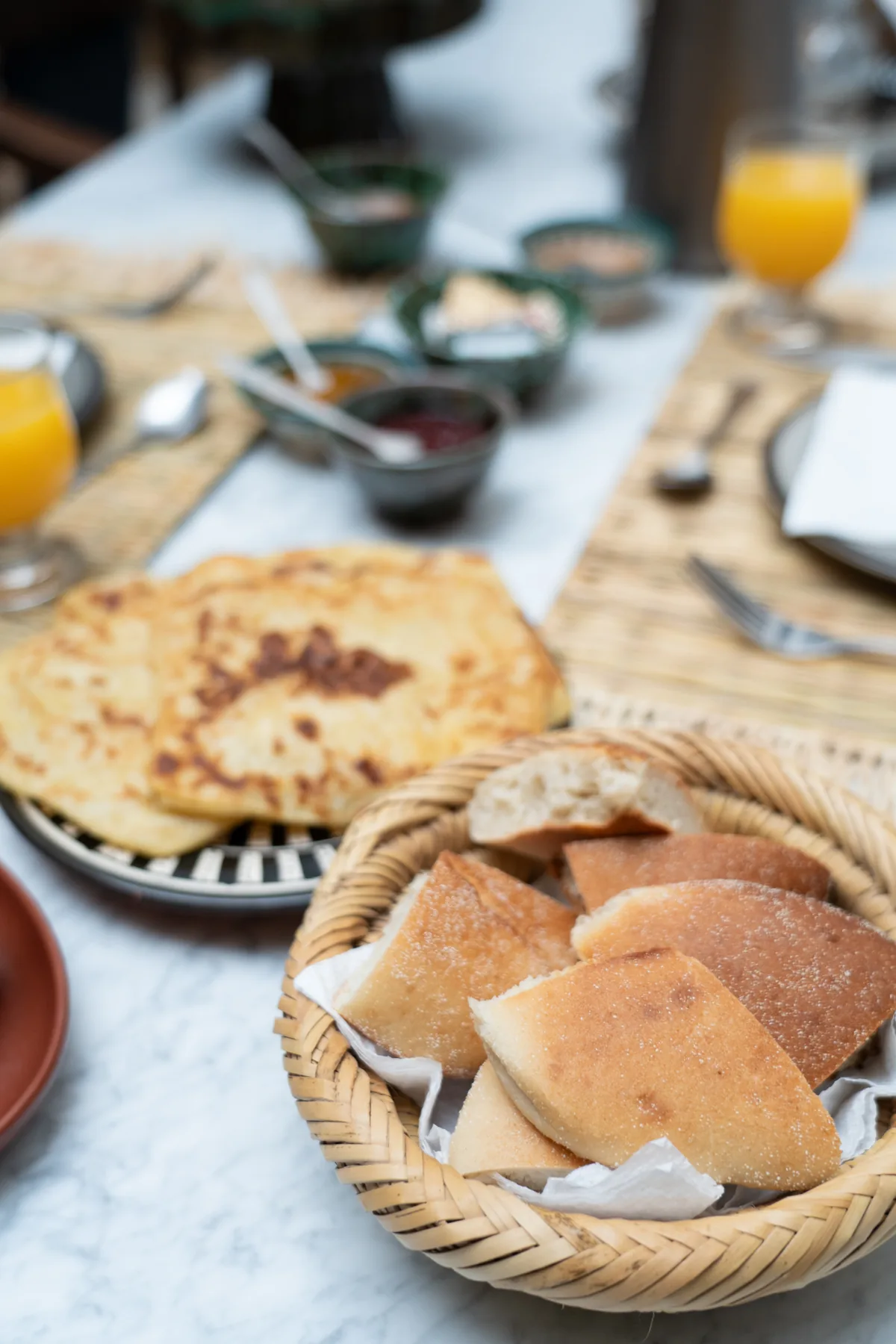 Cesta de panes marroquíes y crepes baghrir en la mesa del desayuno